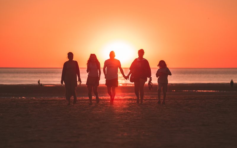 Family walking on beach in sunset
